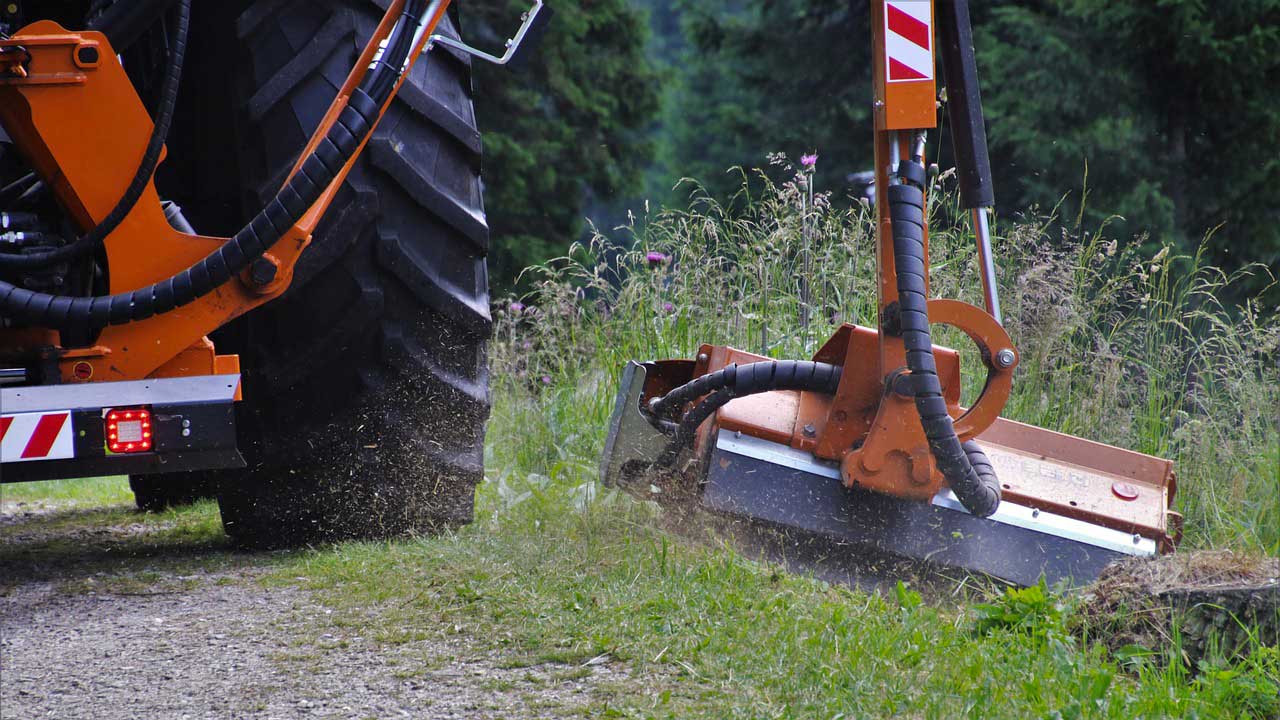 Photo d'un engin paysager entrain de couper l'herbe en bordure de route